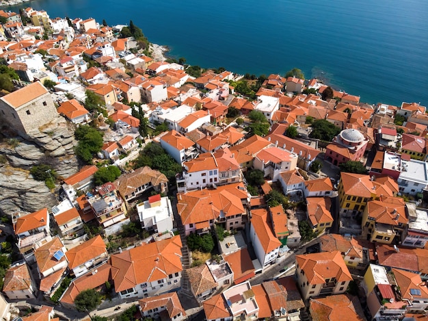 Несколько зданий с оранжевыми крышами, расположенные на побережье Эгейского моря.
