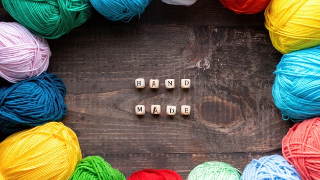 Multiple colored balls of yarn with wooden letters composing words hand made. Top view