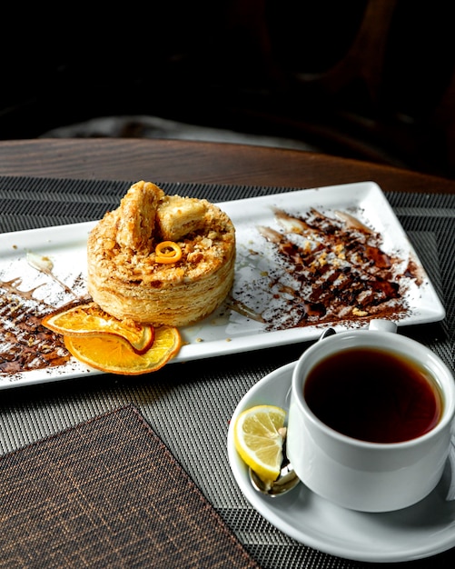 Foto gratuita dessert a più strati con fettine di arancia e una tazza di tè