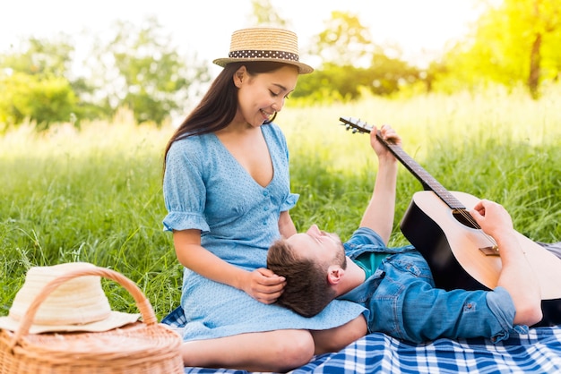 Multiracial adult couple enjoying guitar 