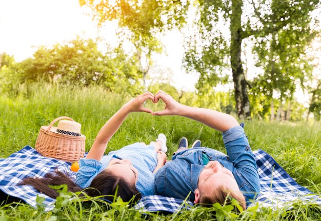 Multiracial adult couple making heart sign with fingers