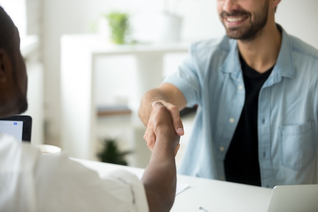 Multiracial businessmen shaking hands, multi-ethnic partnership concept, close up view