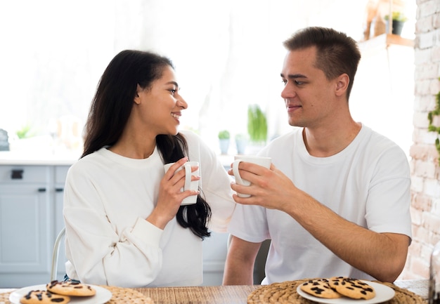 Multiracial couple drinking from cup at home