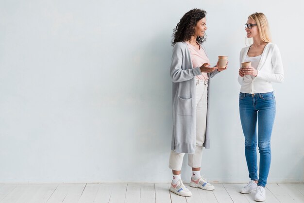 Multiracial employees standing and holding cups on white background