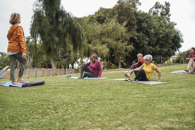 Многорасовые люди занимаются йогой на открытом воздухе в городском парке