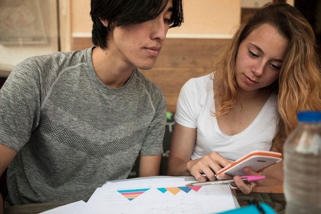 Free photo multiracial young couple looking in calculator near diagrams on paper