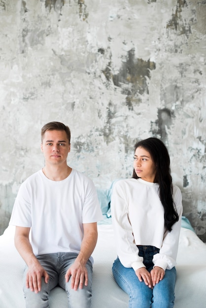 Free photo multiracial young couple sitting side by side