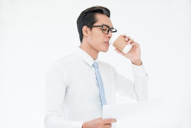 Multitasking man drinking coffee and using phone