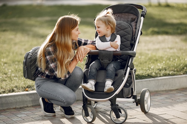 Free photo mum on city street. woman with her toddler sitting in a pram. family concept.