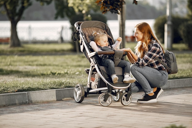 Mum on city street. Woman with her toddler sitting in a pram. Family concept.