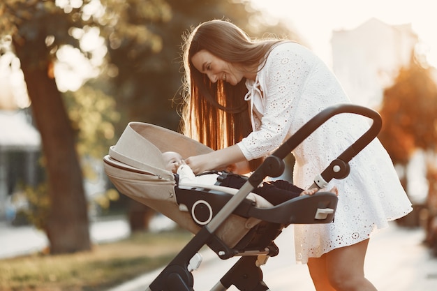 mum walking on city street. woman pushing her toddler sitting in a pram. family concept.