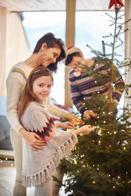 Mummy and girl standing next to the Christmas tree