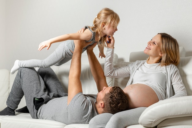 mummy watching father playing with little girl on sofa