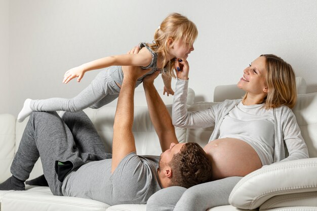 Mummy watching father playing with little girl on sofa