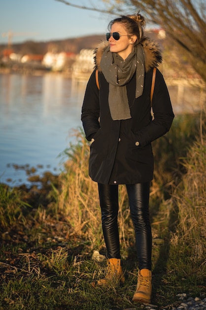 ミュンヘン、ドイツ-2020年11月22日：ミュンヘン近くのアマー湖で夕日を楽しむ若い女性の肖像画