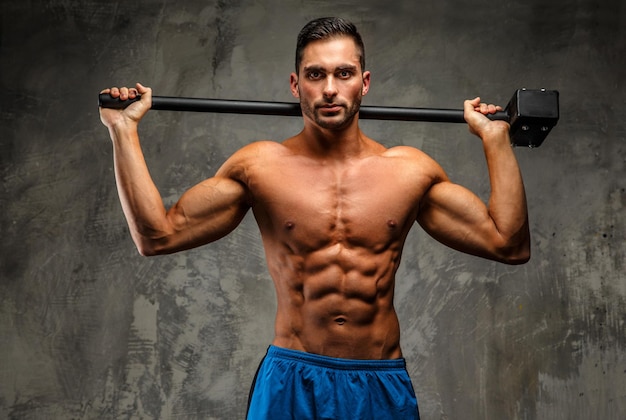 Muscular attractive guy in blue shorts holding hummer on grey background