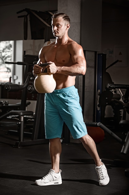 Muscular bodybuilder guy doing exercises with weight in gym