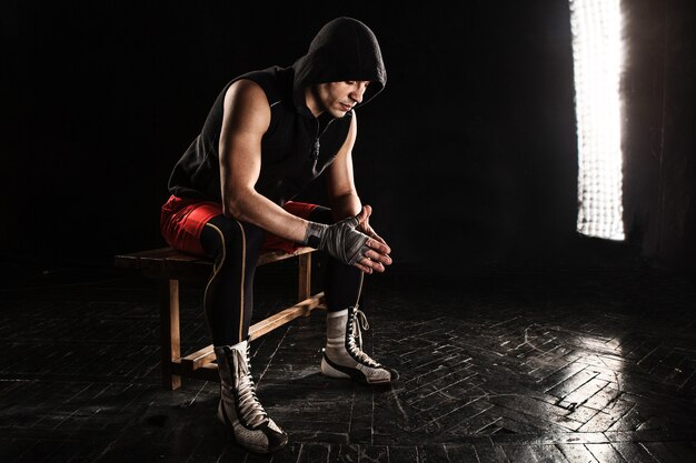 The muscular boxer sitting and resting on black