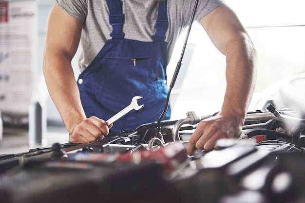 muscular car service worker repairing vehicle.