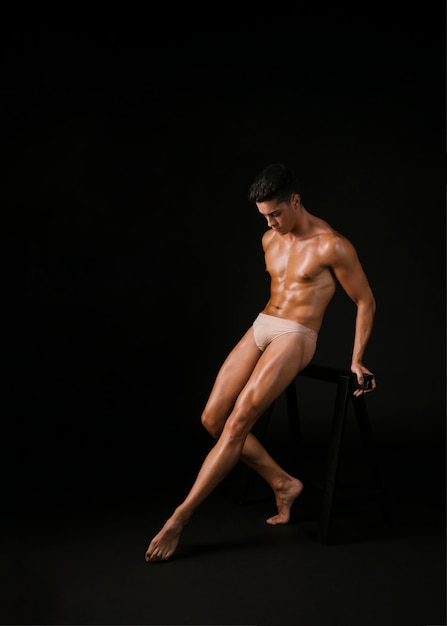 Muscular dancer leaning on barre