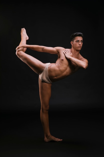 Muscular dancer stretching leg and shoulder