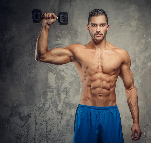 Muscular guy in blue shorts posing in studio.