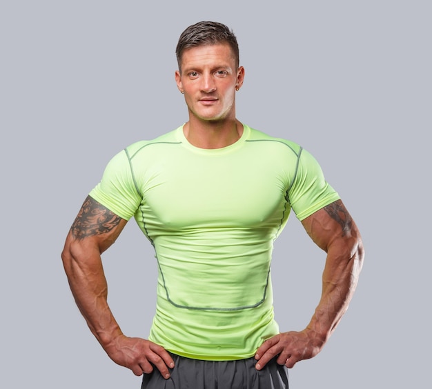 Muscular guy in green sportswear. Isolated on grey