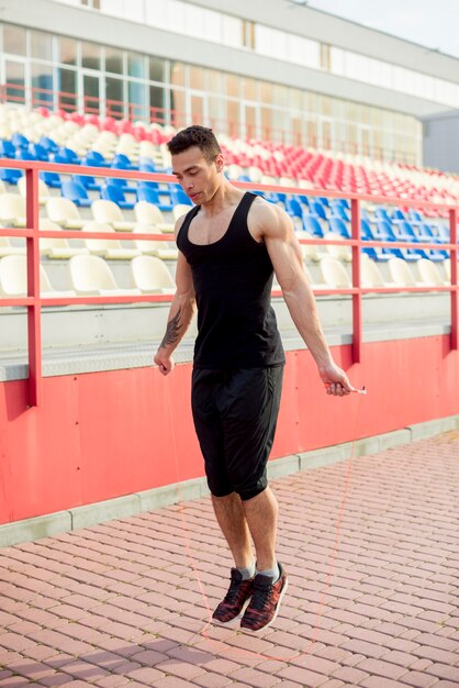 Muscular male athlete skipping in front of arena at stadium