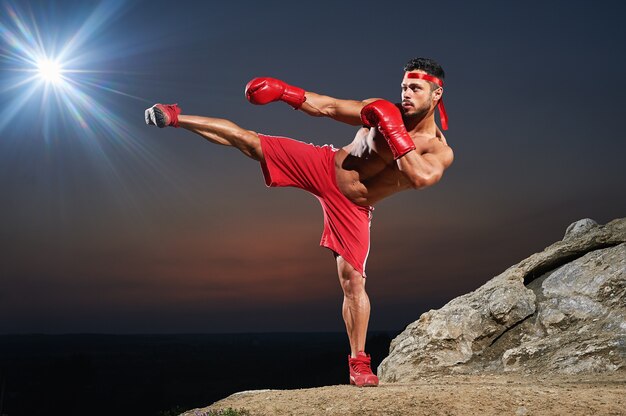 Muscular male boxer training outdoors