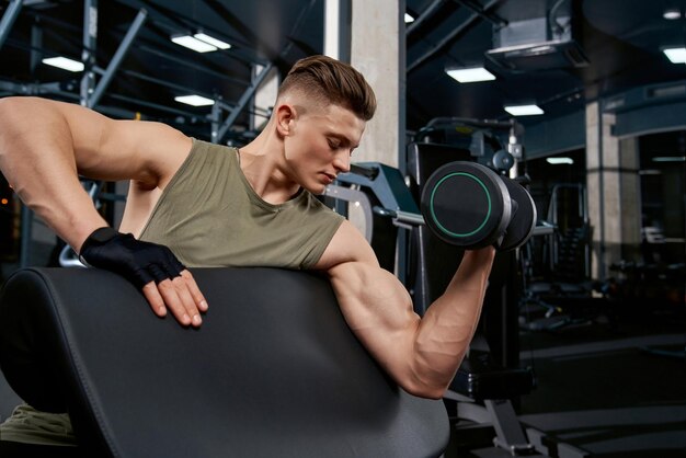 Muscular man building biceps with dumbbell