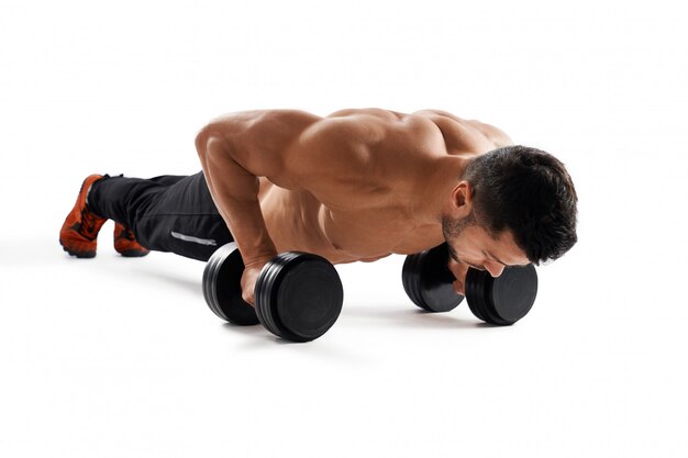 Muscular man doing push ups using dumbbells.