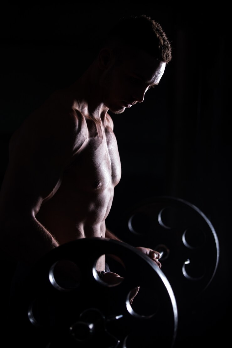 Free Photo muscular man doing weightlifting in fitness center