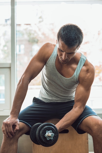 Muscular man doing workout with dumbbells