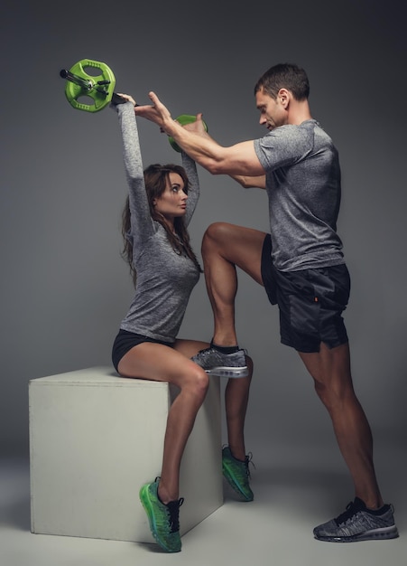 筋肉質の男性がトレーニングで女性を助けます。