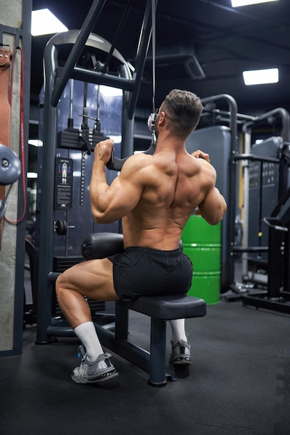 Muscular man pulling training apparatus while exercising in gym