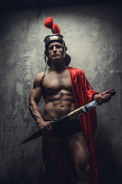 Мускулистый мужчина в римских доспехах с мечом и шлемом.