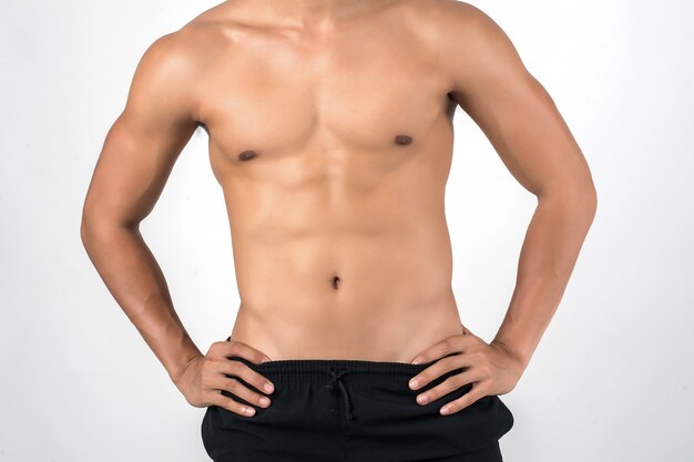 Muscular man showing six pack abs isolated on white background.