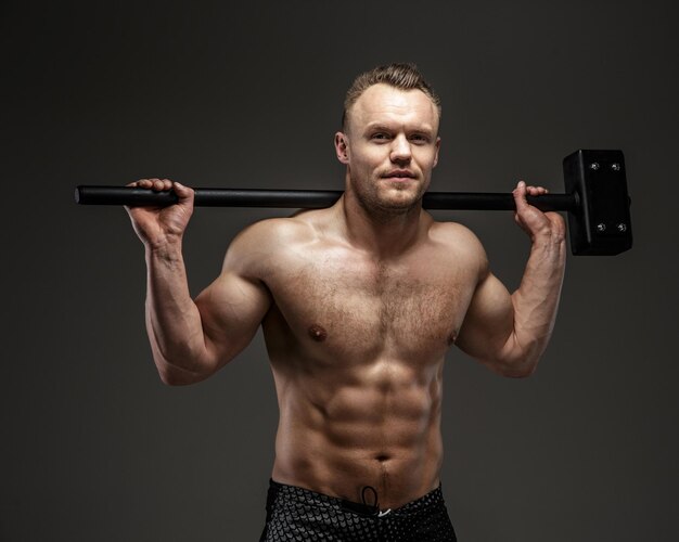 Muscular man with naked torso holding big hummer. Isolated on grey background