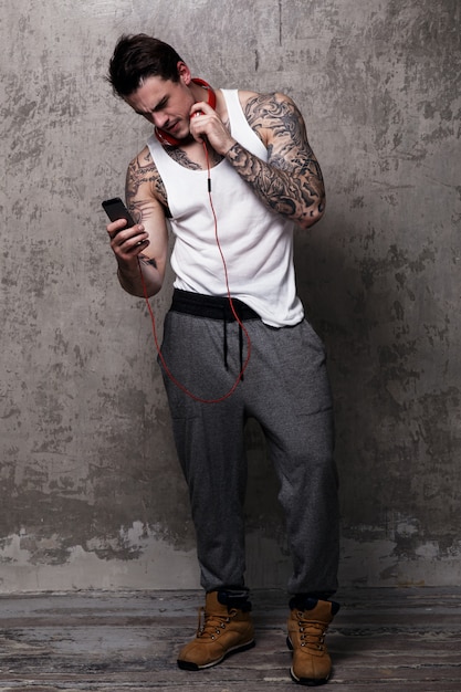 Free photo muscular man with tattoo listening to music