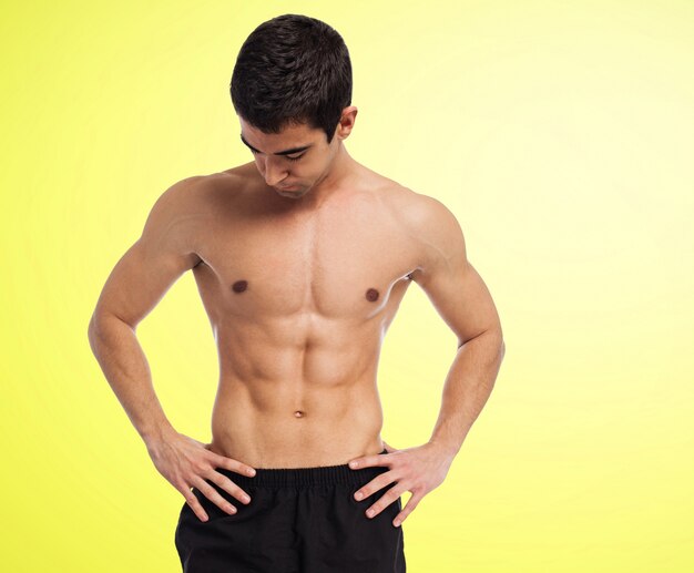 Muscular man without shirt with yellow background