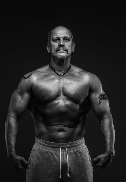 Muscular middle age man posing in studio. Isolated on grey