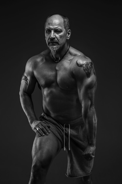 Muscular middle age man posing in studio. Isolated on grey