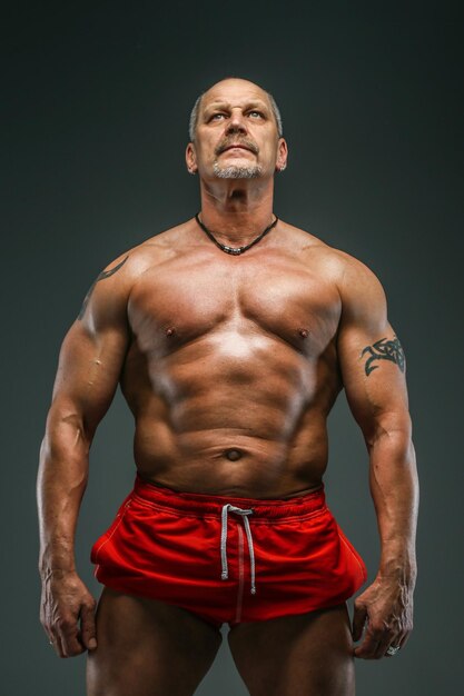 Muscular middle age man posing in studio. Isolated on grey