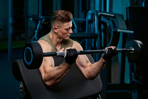 Muscular sportsman building biceps with barbell