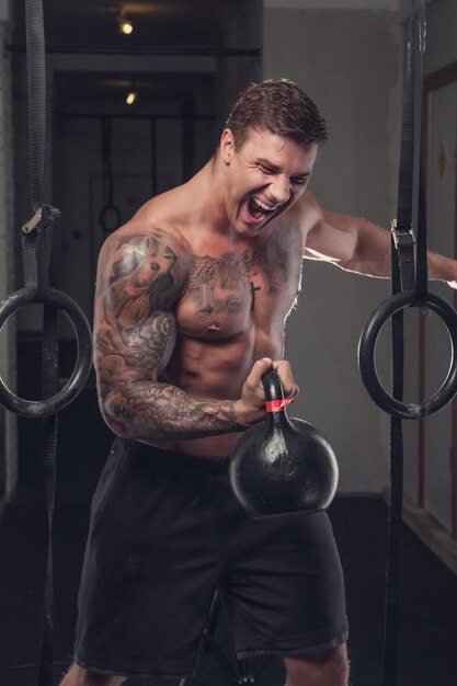 筋肉の入れ墨の男は、持ち上げ重量を保持します。