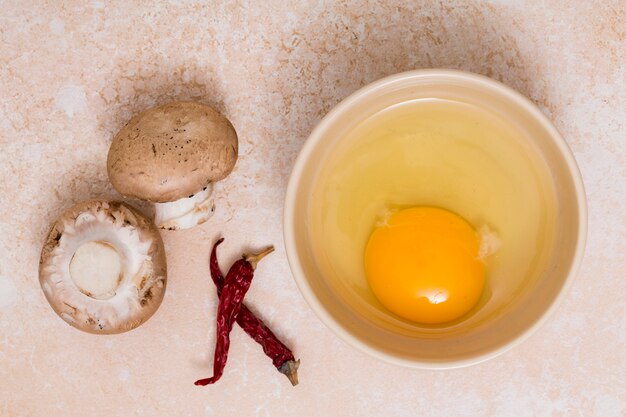 버섯; 질감 된 배경에서 칠리 페 퍼와 계란 노 른 자 그릇