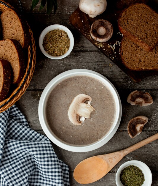 Mushroom cream soup with cream in a white bowl and basket