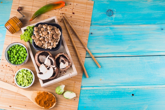 Free photo mushroom; green peas; brussels sprouts; and spice on placemat over the wooden background