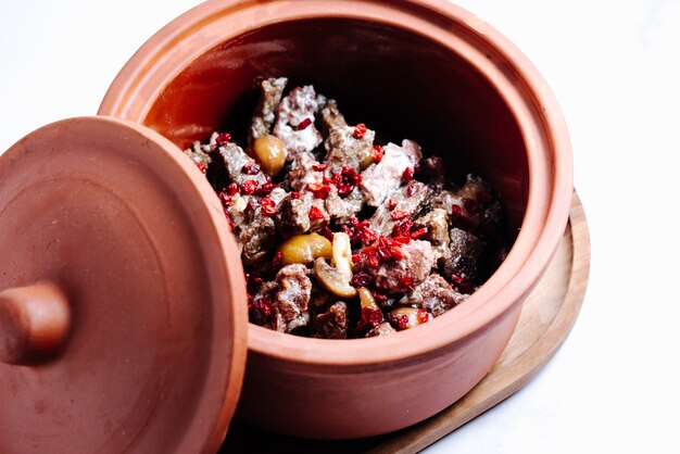 Mushroom and meat slices in pot topped with dried barberry