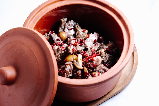 Mushroom and meat slices in pot topped with dried barberry